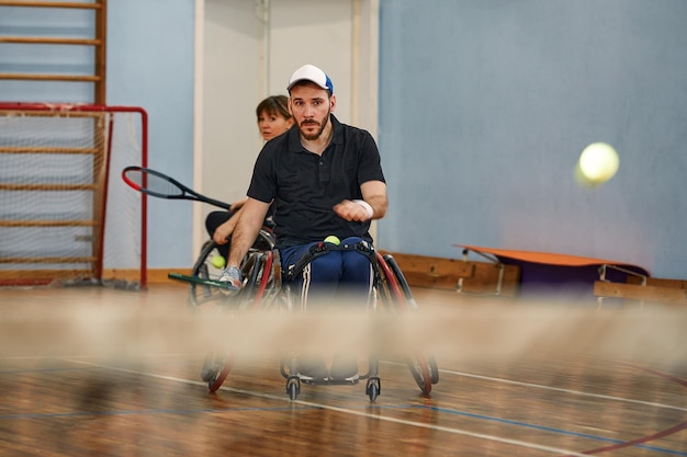 Personnes en fauteuil roulant jouant au tennis sur le court Tennis en fauteuil roulant pour handicapés