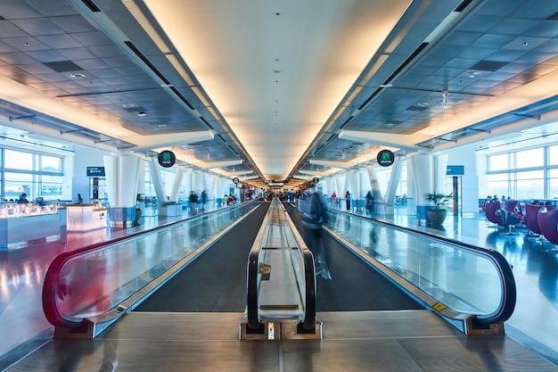 Des personnes floues se déplaçant à travers l'aéroport avec directement sur la vue de deux allées en mouvement