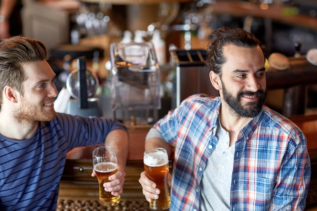 personnes, hommes, loisirs, amitié et concept de fête - amis masculins heureux buvant de la bière pression au bar ou au pub