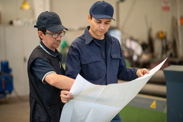 Personnes lisant un dessin dans une usine industrielle