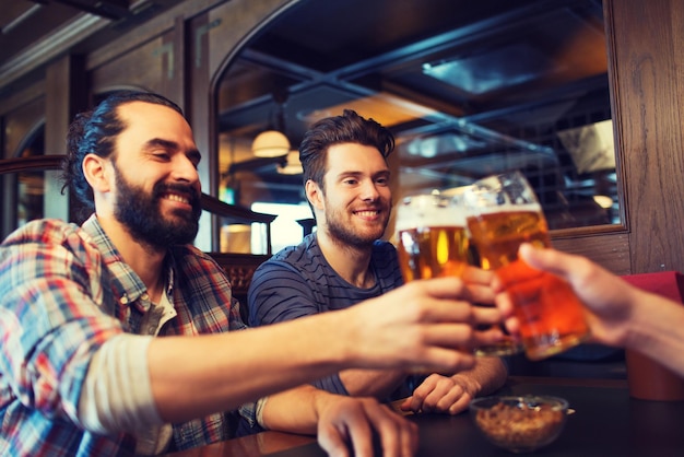 personnes, loisirs, amitié, enterrement de vie de garçon et concept de célébration - amis masculins heureux buvant de la bière et trinquant au bar ou au pub