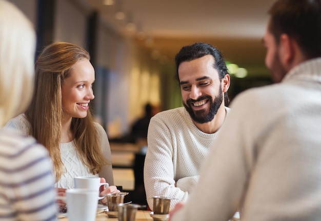 personnes, loisirs, communication, manger et boire concept - amis heureux se rencontrant et buvant du thé ou du café au café