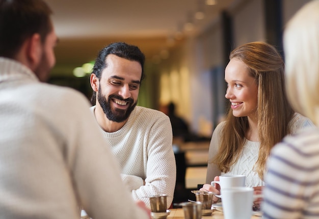 personnes, loisirs, communication, manger et boire concept - amis heureux se rencontrant et buvant du thé ou du café au café