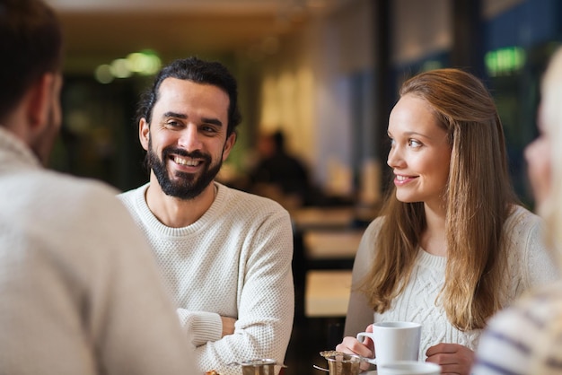 personnes, loisirs, communication, manger et boire concept - amis heureux se rencontrant et buvant du thé ou du café au café