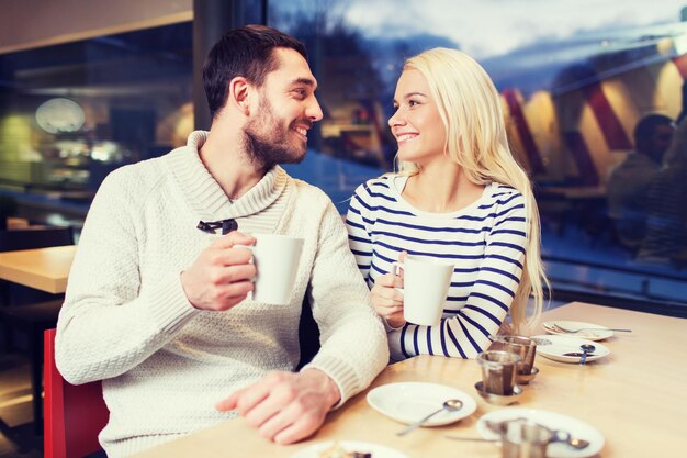 personnes, loisirs, communication, manger et boire concept - couple heureux se rencontrant et buvant du thé ou du café au café