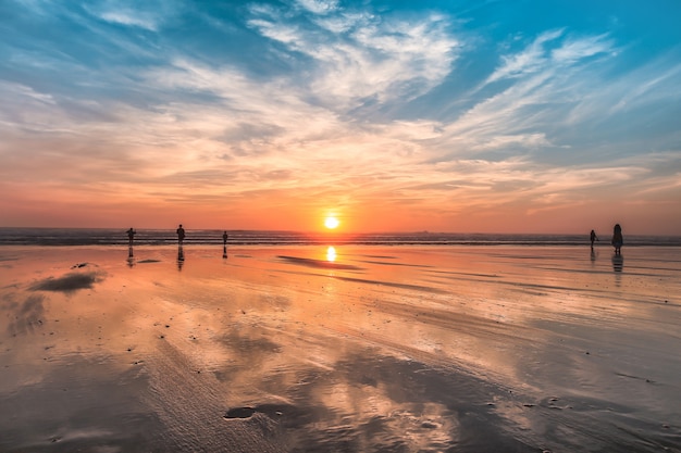 Personnes marchant sur la plage pendant le coucher du soleil coloré