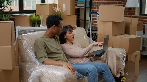 Des personnes mariées emménageant ensemble et regardant la décoration de la maison pour acheter en ligne un nouvel appartement. Acheter des meubles d'intérieur sur un ordinateur portable, après avoir acheté l'investissement des ménages.