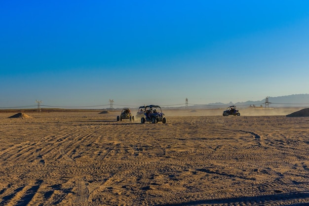 Des personnes méconnaissables conduisant des buggys lors d'un safari au coucher du soleil dans le désert d'Arabie non loin de la ville d'Hurghada en Égypte