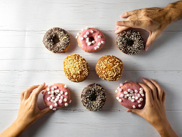 Des personnes méconnaissables ramassent Donut sur une table en bois Vue de dessus Pose à plat