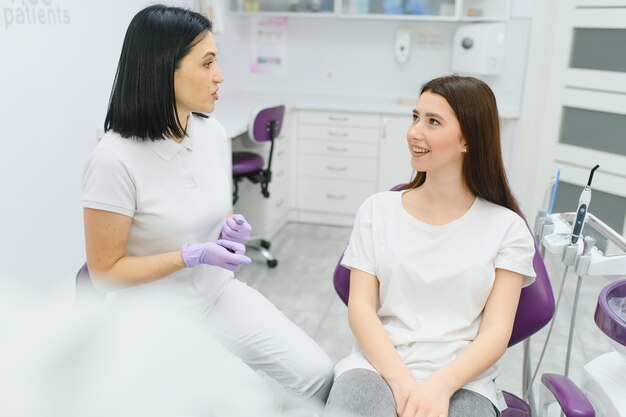 Personnes médecine stomatologie et concept de soins de santé heureuse femme dentiste avec une patiente parlant au bureau de la clinique dentaire