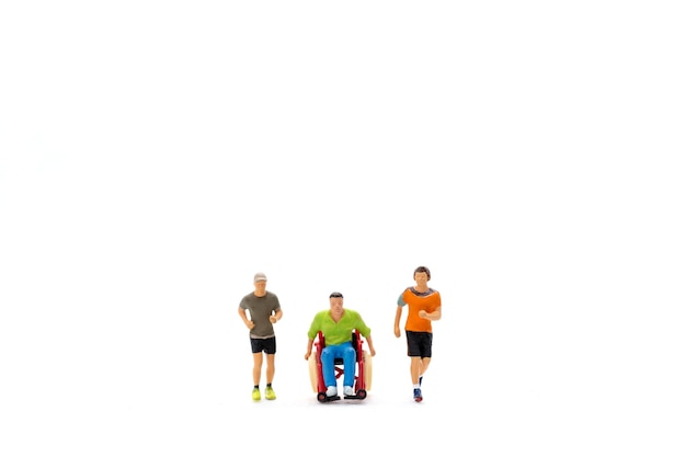 Des personnes en miniature handicapées, des amis heureux s'amusant ensemble sur un fond blanc.