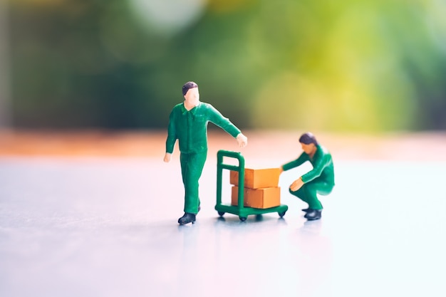 Personnes miniatures, couple homme portant une boîte utilisant pour le concept logistique et commercial