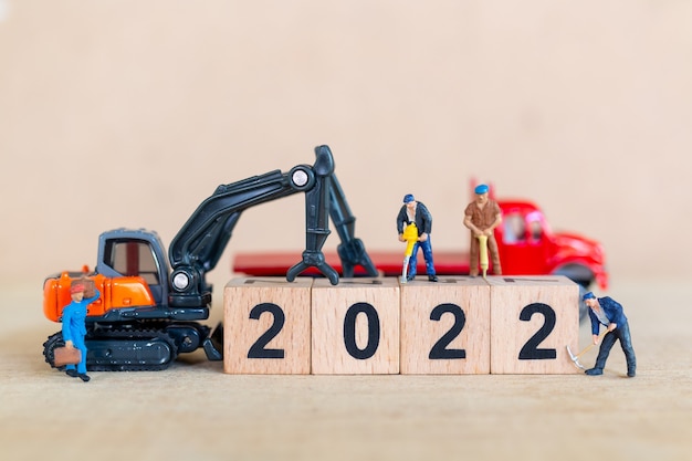 Personnes miniatures : L'équipe de travailleurs crée le numéro de bloc en bois 2022, concept de bonne année