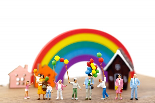 Les personnes miniatures, la famille et les enfants s’amusent avec des ballons colorés.