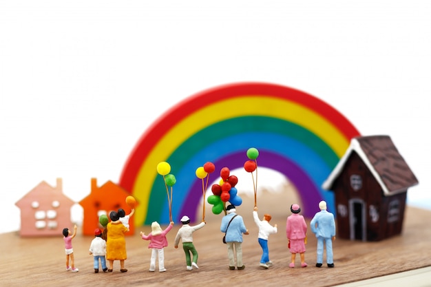 Les personnes miniatures, la famille et les enfants s’amusent avec des ballons colorés.