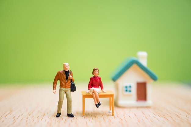 Les personnes miniatures, femme et homme restent en face de la maison sur fond vert, utiliser pour les busines