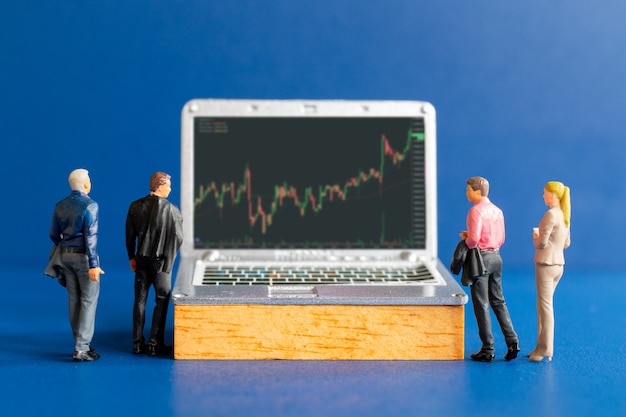 Personnes miniatures, gens d'affaires consultant des conseillers financiers professionnels et des tablettes comportant des téléscripteurs boursiers, un graphique boursier ou de trading forex dans un concept graphique