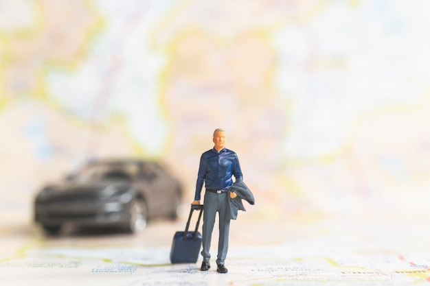 Personnes miniatures Homme d'affaires avec bagages marchant sur les concepts de carte, de voyage et d'aventure