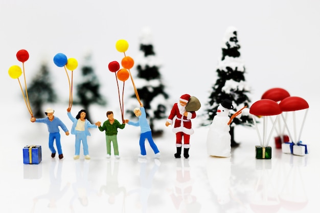 Personnes miniatures: Père Noël et enfants tenant un ballon avec arbre de Noël.