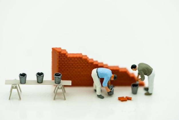 Personnes miniatures travaillant sur un mur