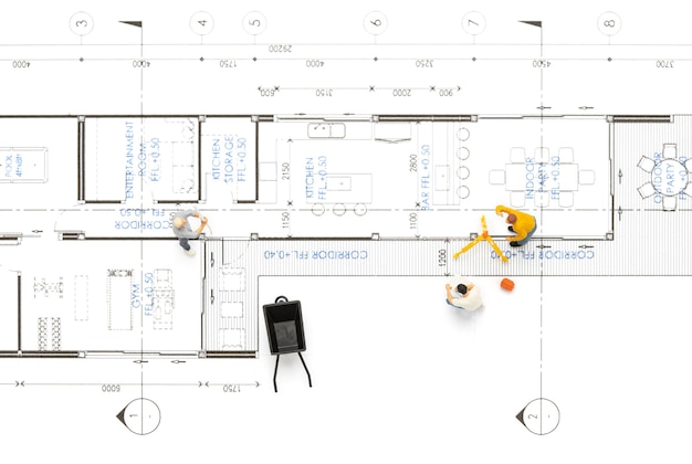 Personnes miniatures travaillant sur un plan de maison