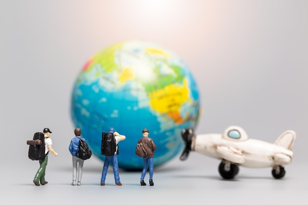 Personnes miniatures Voyageurs avec avion et globe, concepts de voyage et d'aventure