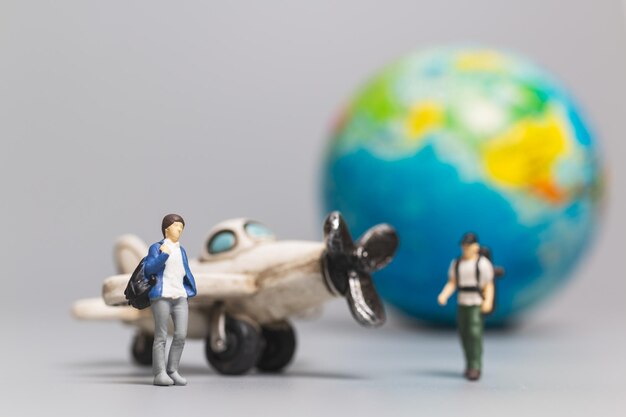 Personnes miniaturesT ravelers avec avion et globe, concepts de voyage et d'aventure