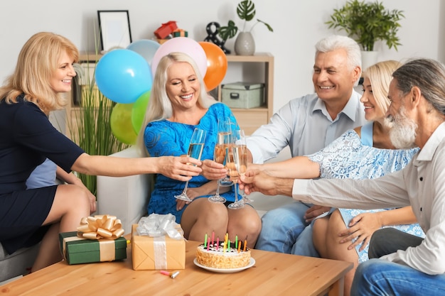 Personnes mûres célébrant l'anniversaire avec du champagne à l'intérieur