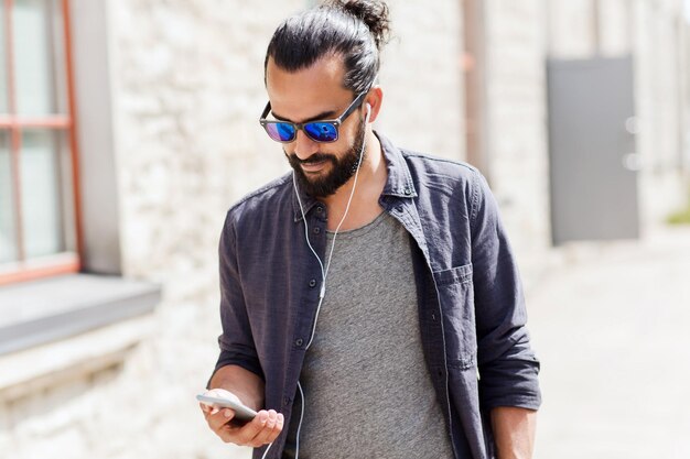 personnes, musique, technologie, loisirs et style de vie - homme avec écouteurs et smartphone marchant en ville