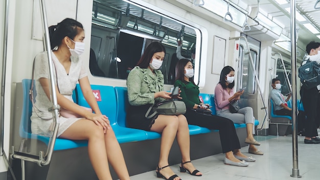 Des personnes portant des masques faciaux dans une rame de métro publique bondée