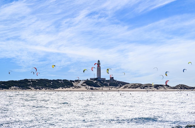 Personnes pratiquant le kitesurf sur la plage de Los Caños de Meca, à côté du phare de Trafalgar.