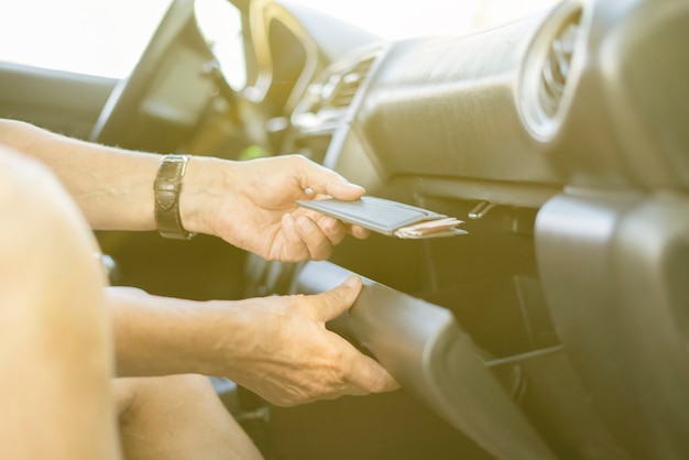 Les personnes prennent à la main de l'argent liquide et une carte de crédit dans la boîte à gants de la voiture