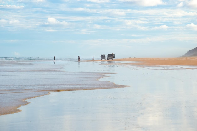 Personnes et quatre roues motrices au bord de la mer dans une journée nuageuse à Fraser IslandQueenslandAustralie