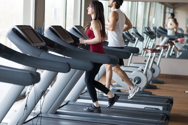 Personnes qui courent sur un tapis roulant dans une salle de sport