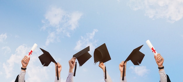 Photo personnes qui ont réussi dans l'éducation tenant une casquette de graduation sur fond de ciel lumineux avec beauté