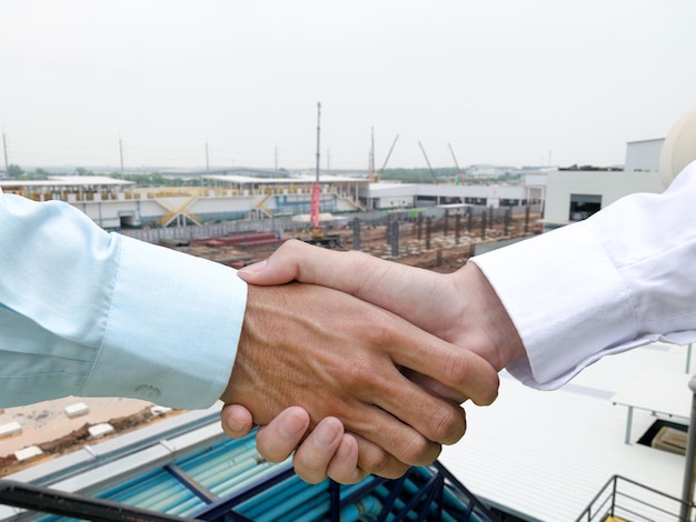 Personnes qui réussissent se serrant la main au concept de poignée de main de fond de construction