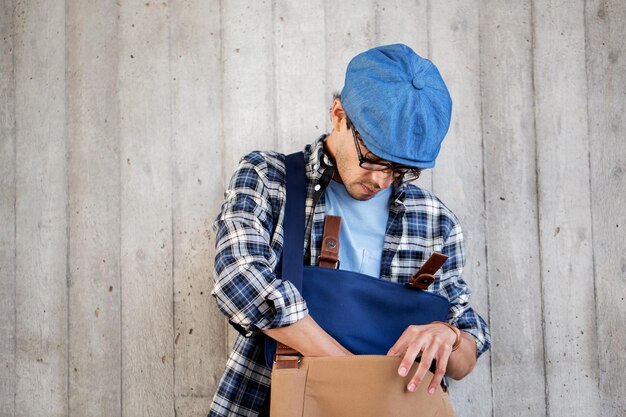 personnes, style, loisirs et style de vie - jeune homme hipster à la recherche de quelque chose dans son sac