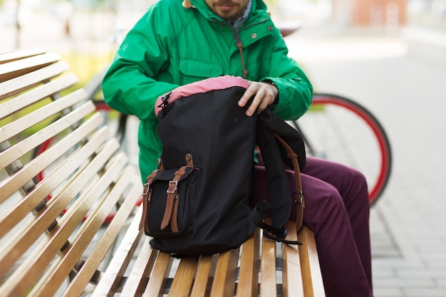 personnes, style, tourisme et style de vie - gros plan d'un homme avec sac à dos sur un banc de la ville