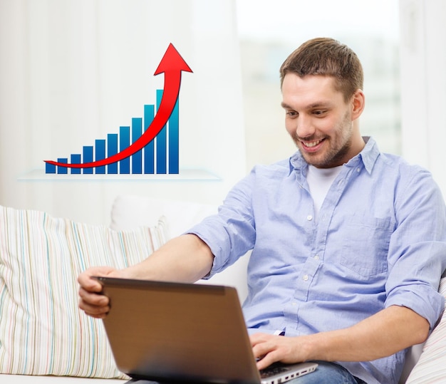 personnes, technologie, statistiques et concept d'entreprise - homme souriant avec ordinateur portable et courbe de croissance assis sur un canapé à la maison