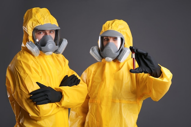 Personnes en tenue de protection chimique avec échantillon de sang sur fond gris Recherche sur les virus