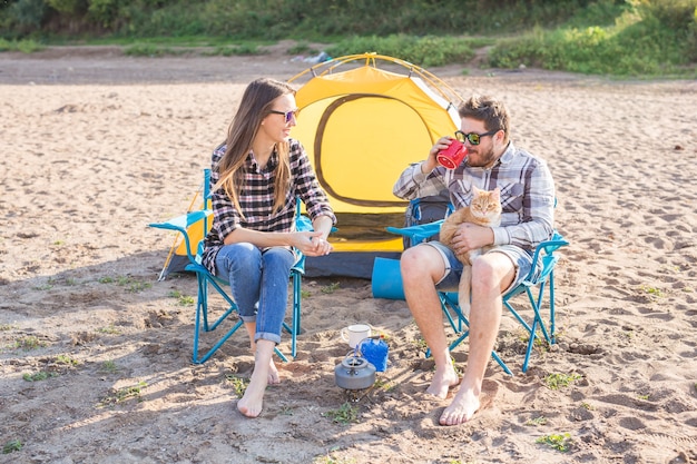 Personnes, tourisme d'été et concept nature - jeune couple buvant du thé près de la tente.