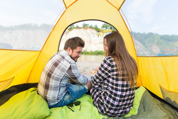 Personnes, tourisme d'été et concept nature - jeune couple se reposant dans une tente de camping, vue de l'intérieur.