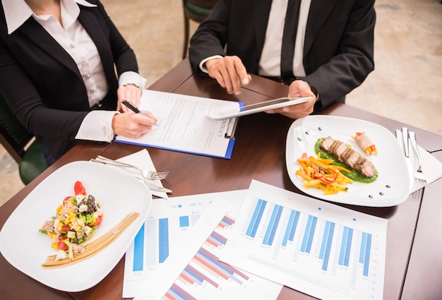 Personnes travaillant sur la stratégie marketing lors d'un déjeuner d'affaires.