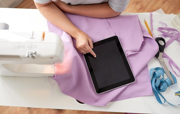 personnes, travaux d'aiguille, technologie et concept de couture - femme sur mesure avec machine à coudre, tablette PC et tissu