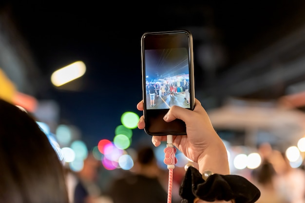 Personnes utilisant des téléphones mobiles Photographier les touristes dans le marché de nuit