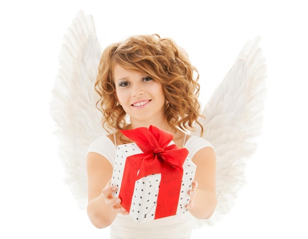 personnes, vacances, noël, anniversaire et concept religieux - jeune femme heureuse avec des ailes d'ange tenant une boîte-cadeau sur fond blanc