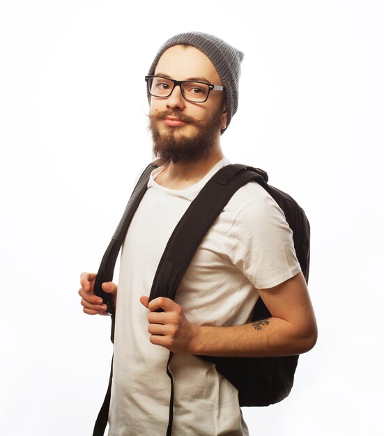 personnes voyage tourisme et éducation concept heureux jeune homme barbu avec des lunettes portant un chapeau avec un sac à dos sur un fond blanc