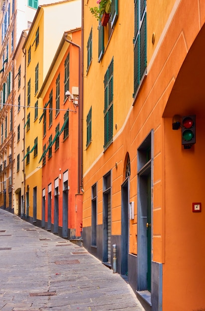 Perspective de la vieille rue en montée avec des maisons pittoresques jaune-orange à Gênes (Genova), Italie