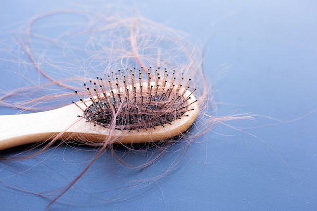 La perte de cheveux tombe en peigne sur fond sombre.