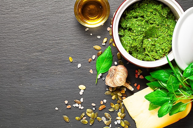 Pesto en pot en céramique et ingrédients sur texturé